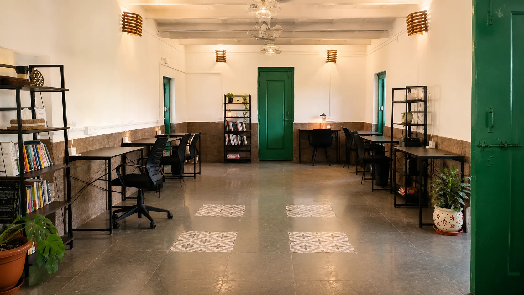 An indoor coworking space with desks and bookshelves at The Haven Goa